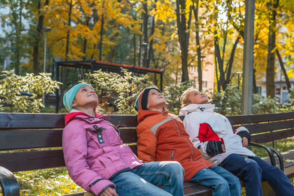 three people sitting on a bench in a park