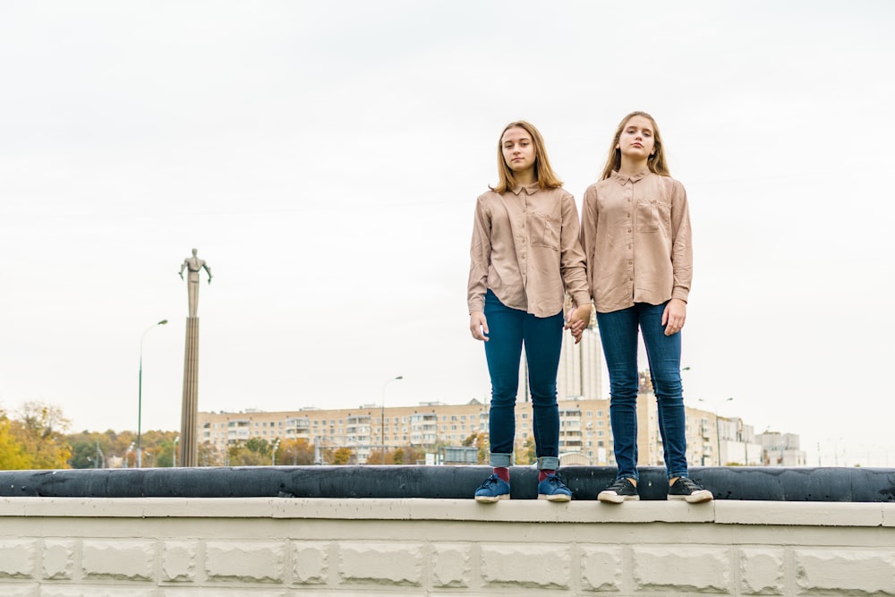 two young women standing on a ledge in front of a building