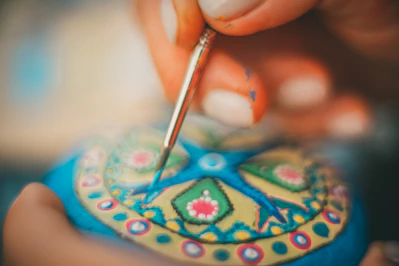 a person is painting a decorative object with a paintbrush
