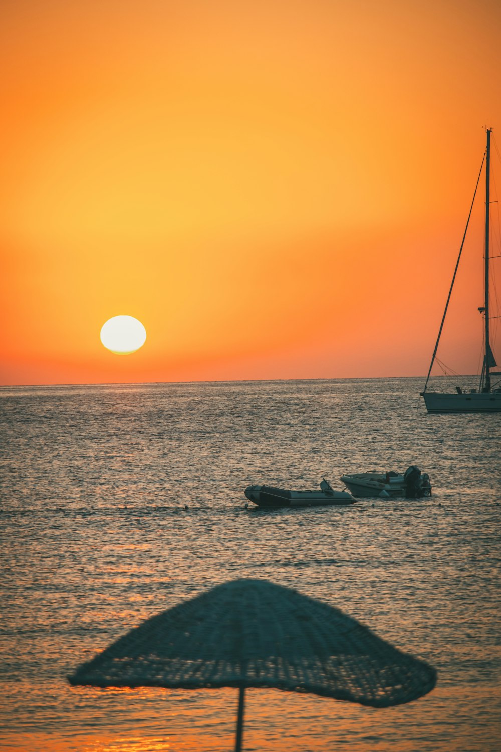 the sun is setting over the ocean with boats in the water