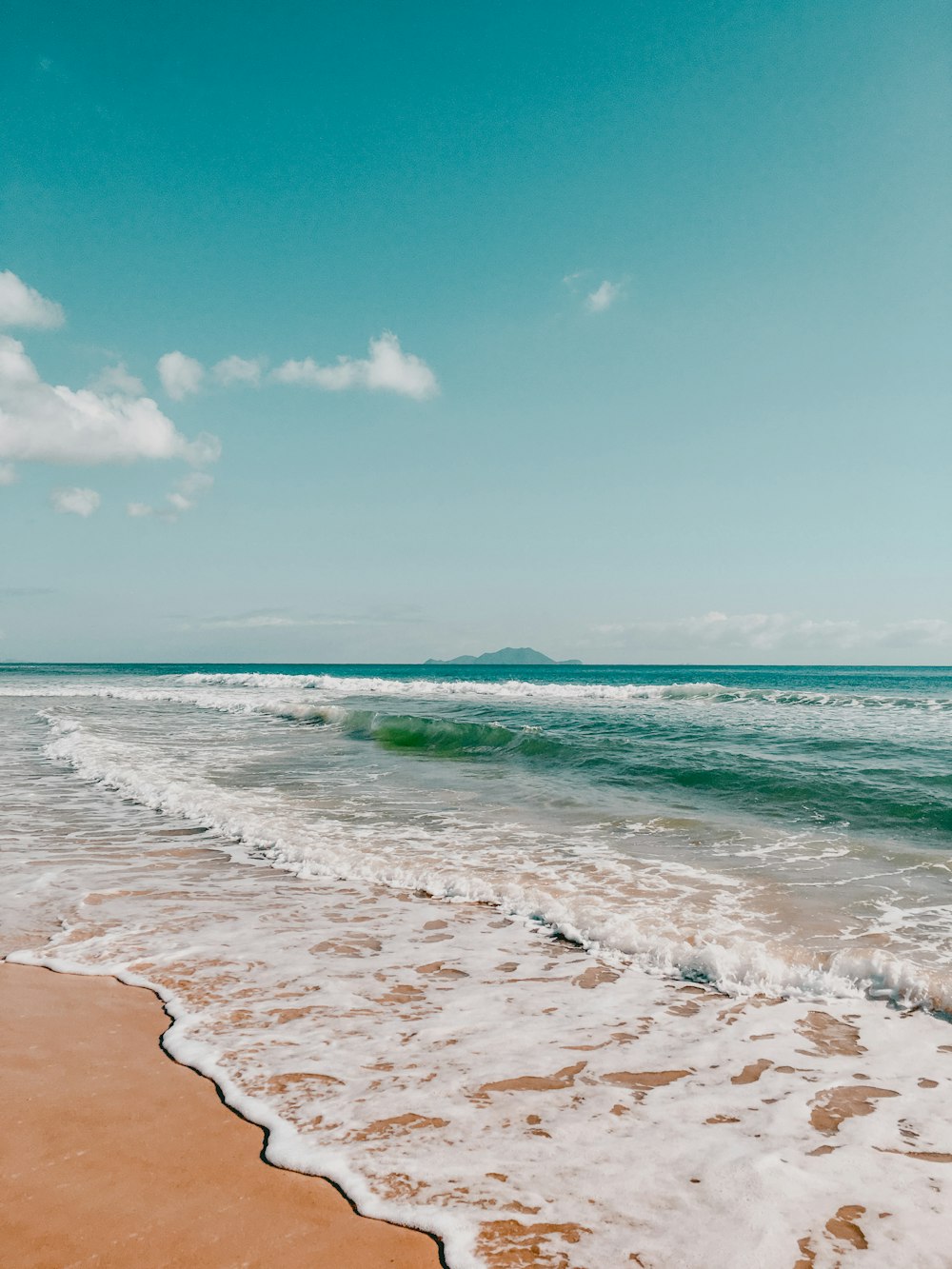 a sandy beach with waves coming in to shore