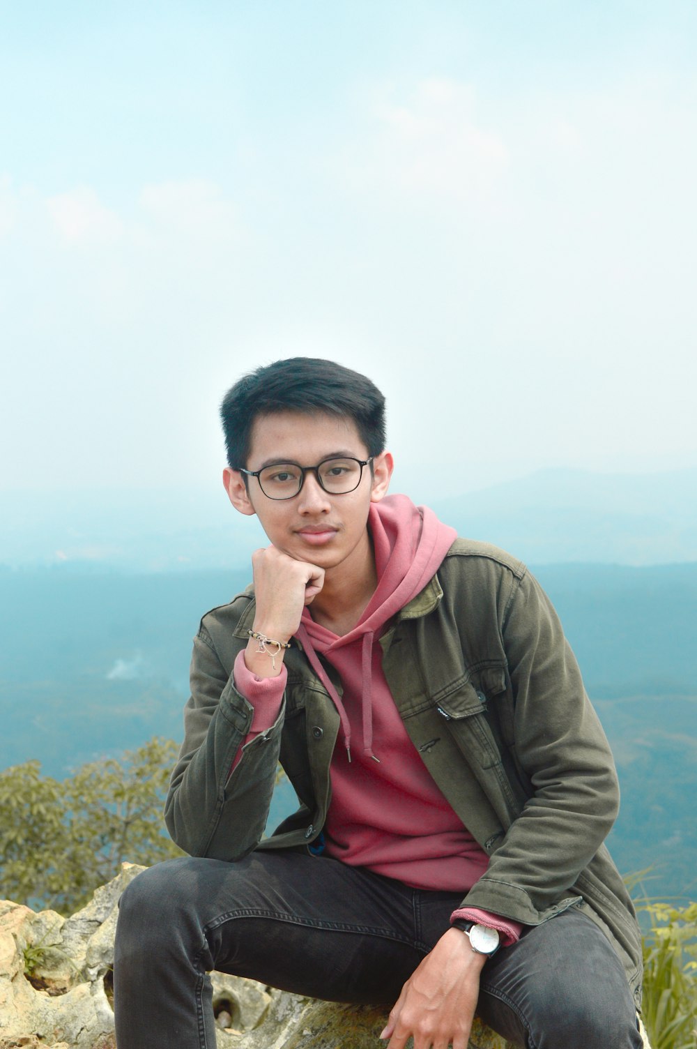 a man sitting on top of a rock next to a mountain