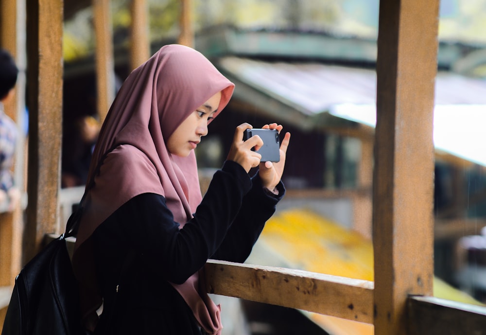 a woman in a hijab is looking at her cell phone