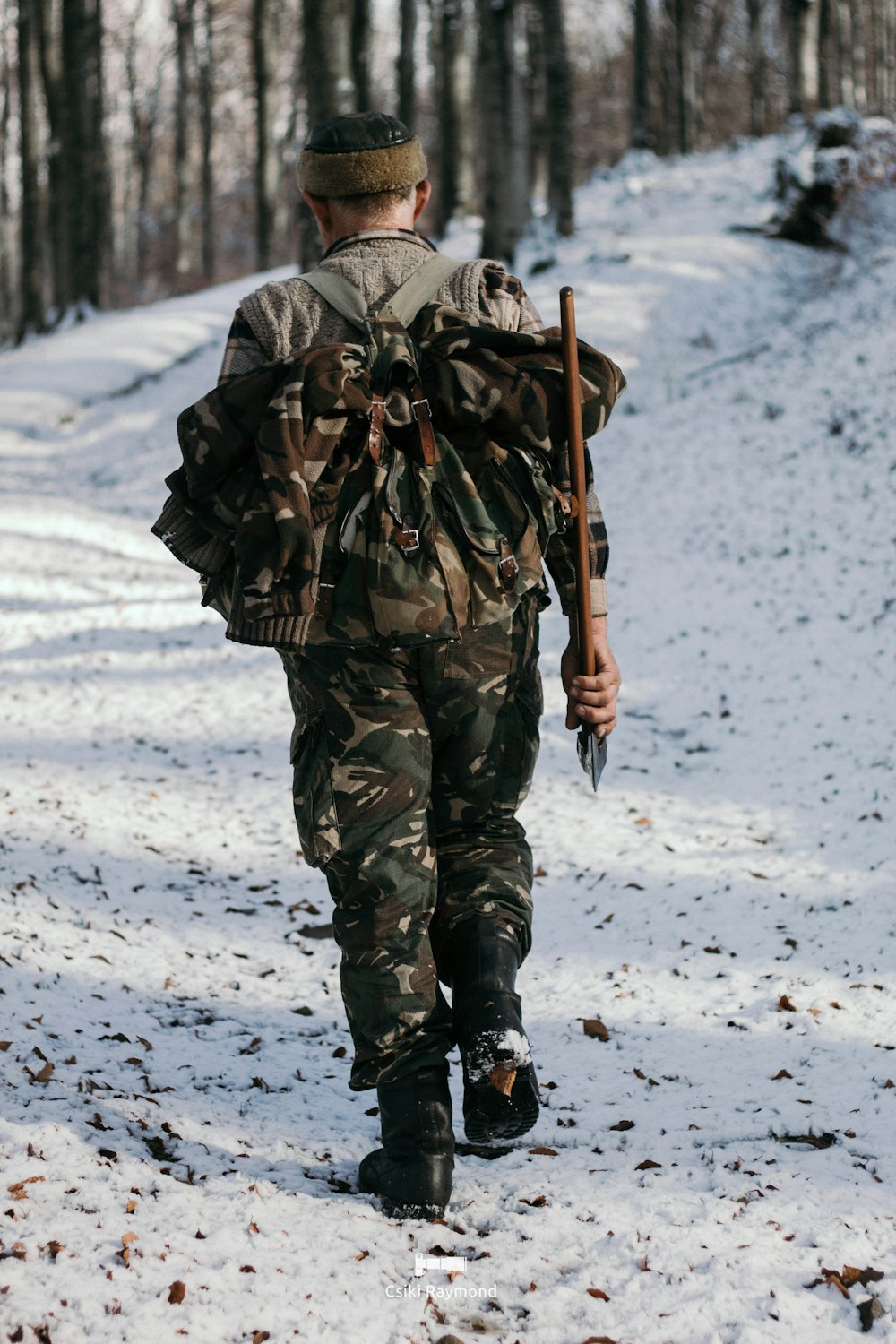 a man in camouflage walking in the snow