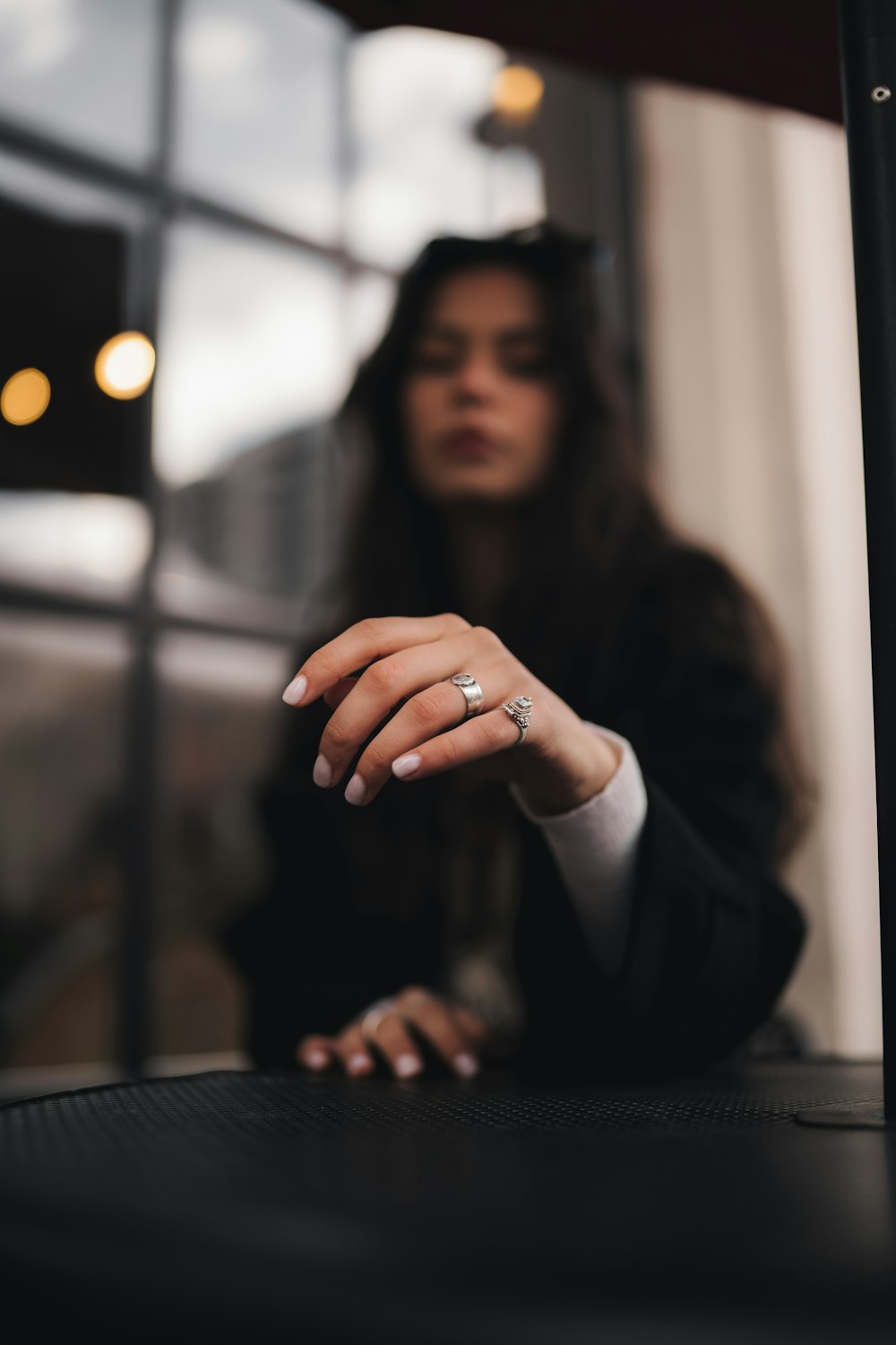 a woman sitting at a table with a ring on her finger