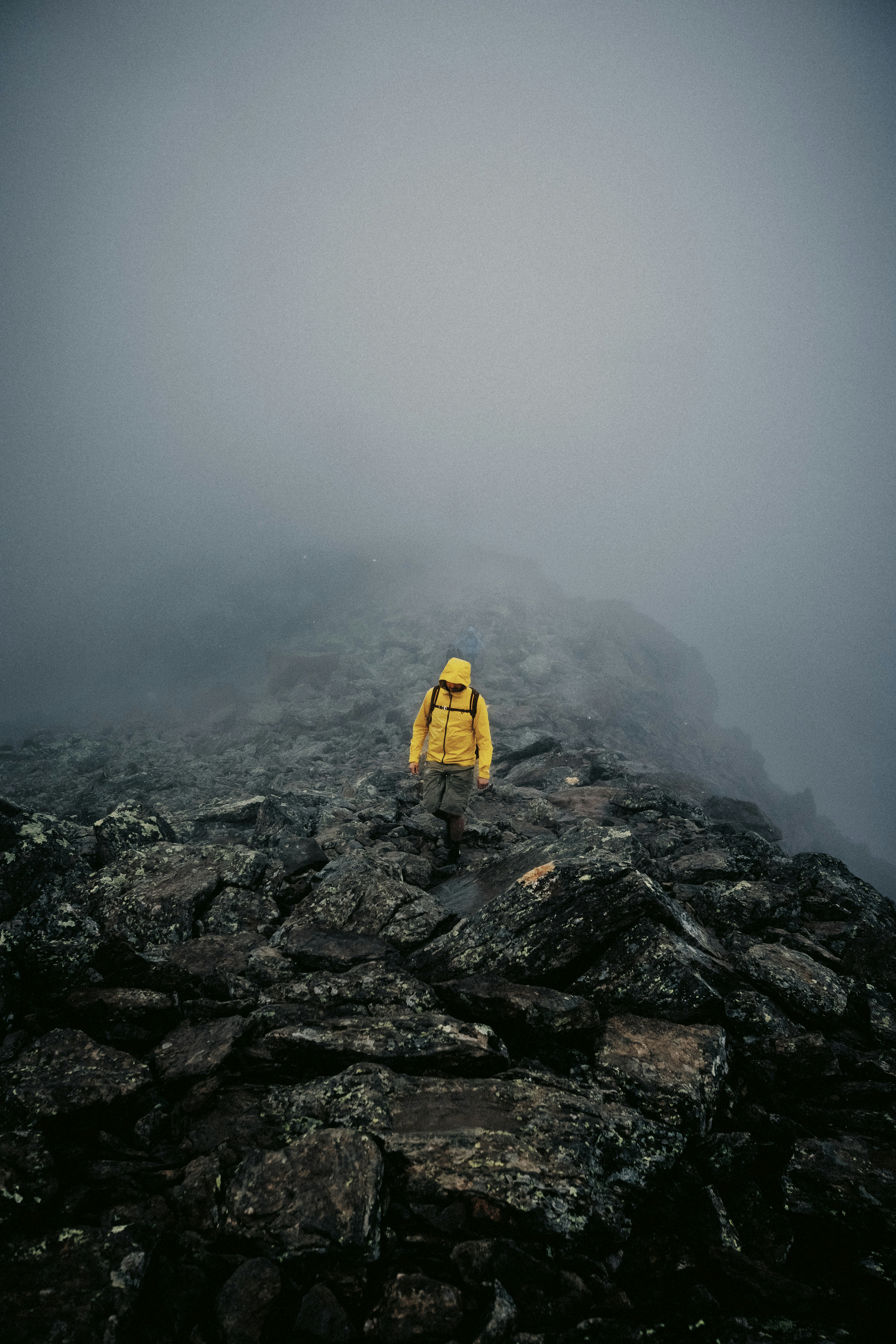 Person wearing a yellow technical shell jacket on a rocky mountain in Austria