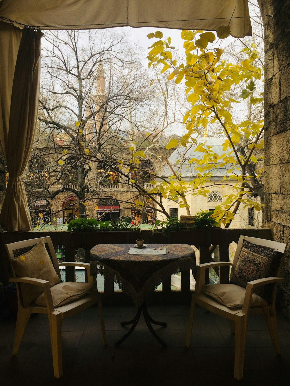 a table and chairs on a balcony with a view of trees