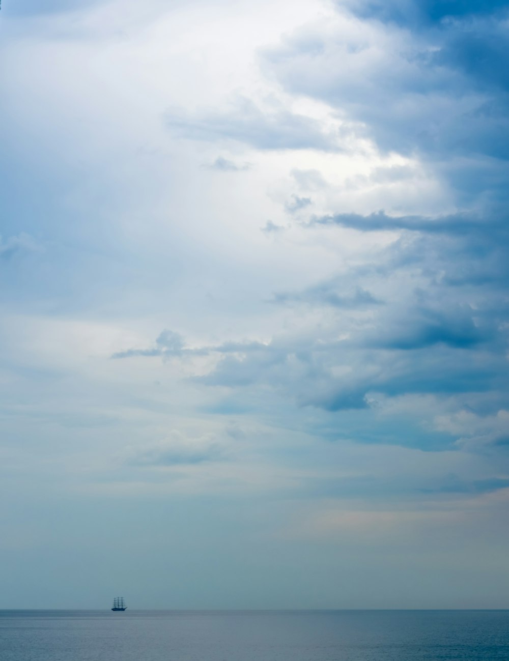 a sailboat in the ocean under a cloudy sky