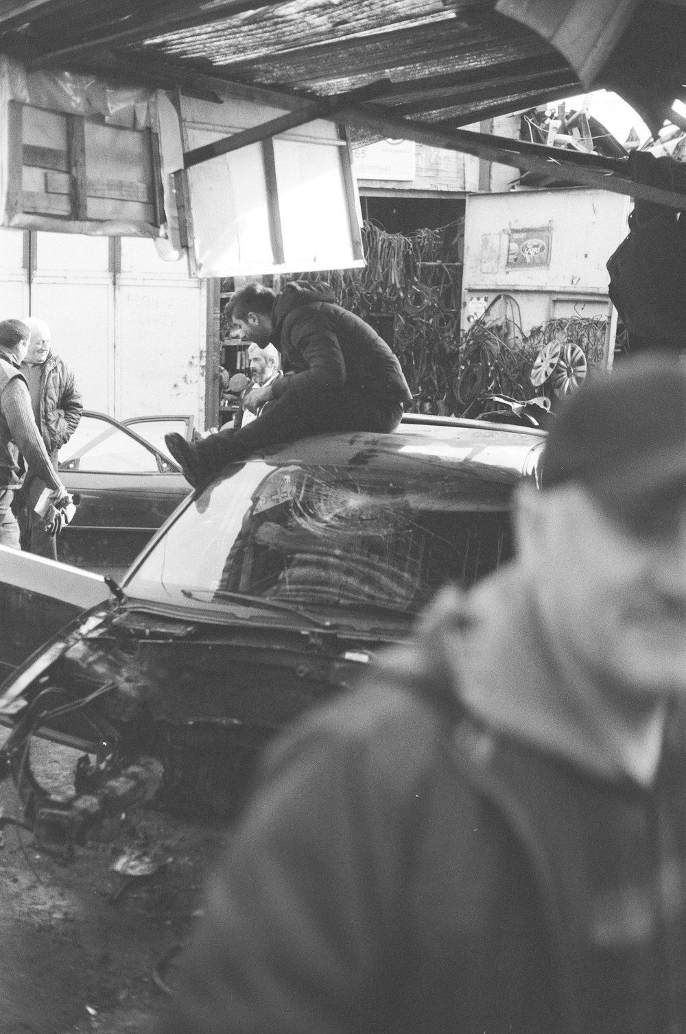 a black and white photo of a cat sitting on top of a car