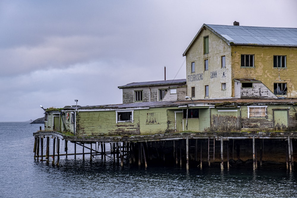 a yellow house sitting on top of a wooden pier