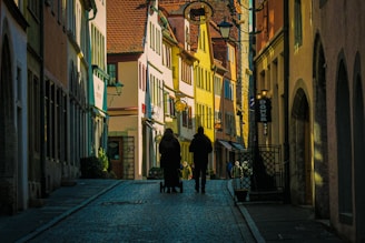 a couple of people walking down a street next to tall buildings