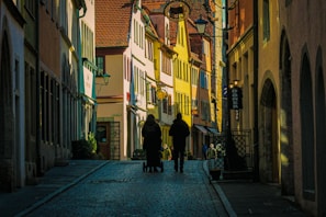 a couple of people walking down a street next to tall buildings