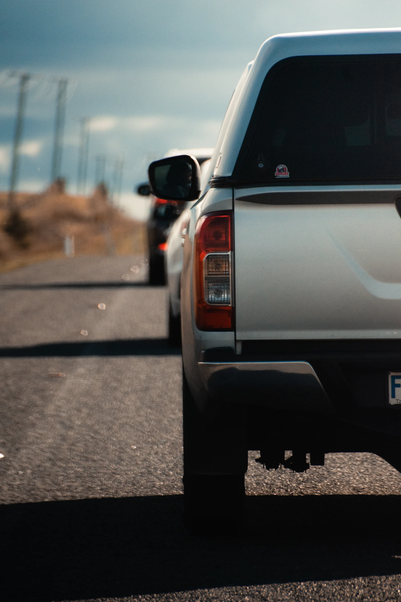 A white goods truck on a highway with a motorcycle riding alongside it.