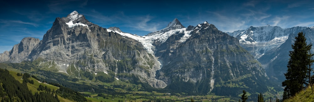 the mountains are covered in snow and green grass