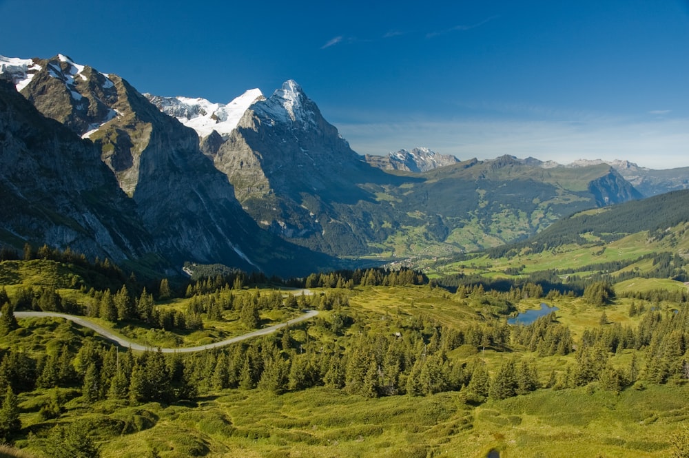 a scenic view of a mountain range with a winding road in the foreground