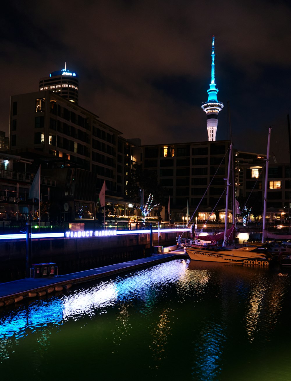 Eine Nachtszene eines Hafens mit Booten und einem Turm im Hintergrund