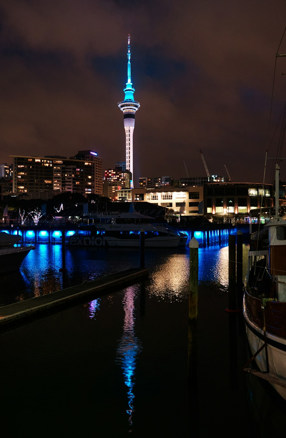 a night scene of a harbor with boats and a tower in the background