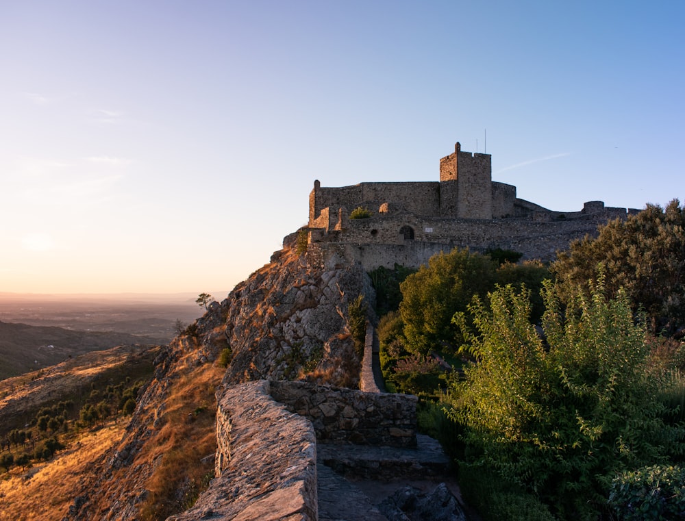 a castle sitting on top of a hill next to a forest