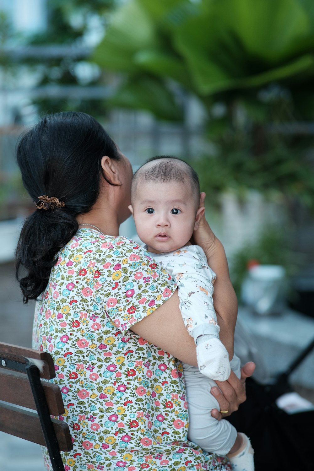 a woman sitting on a bench holding a baby