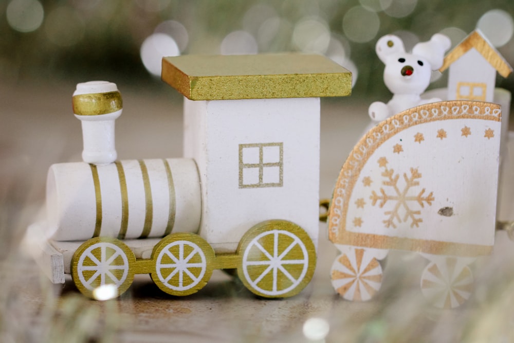 a white and gold train with a teddy bear sitting on top of it