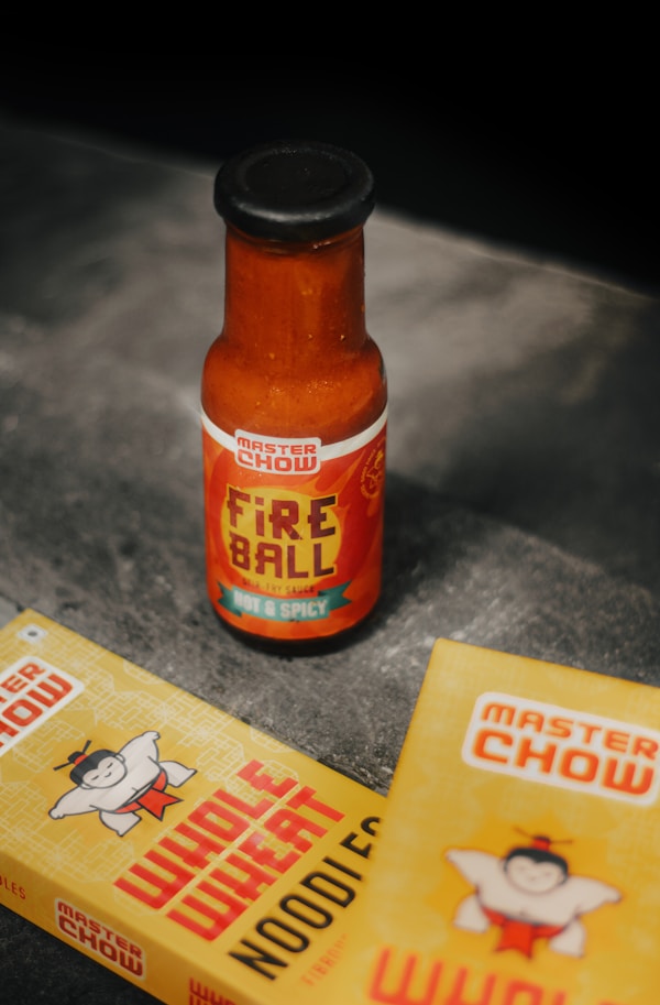 A bottle of hot sauce next to a packet of chips
