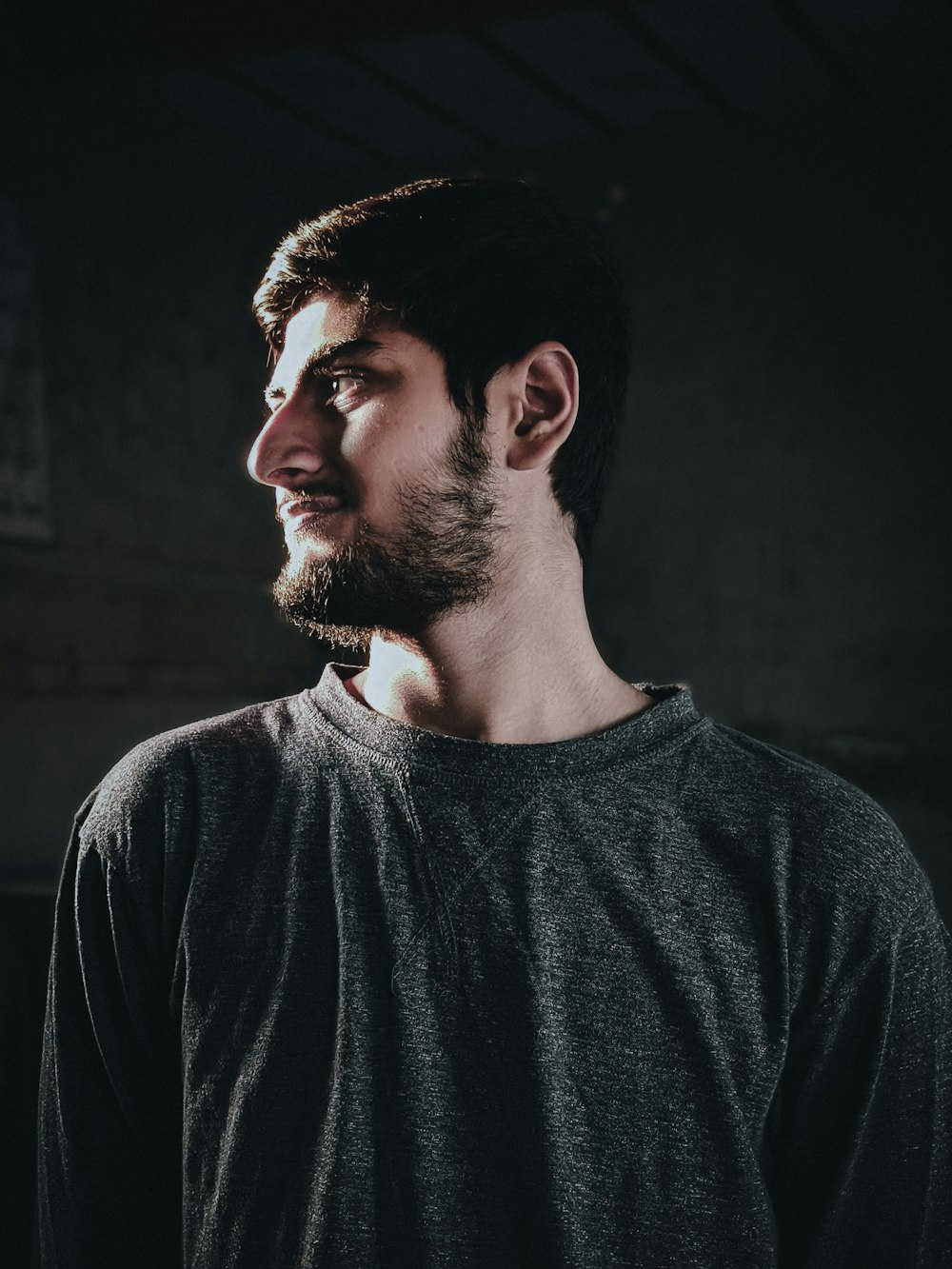 a man with a beard standing in a dark room