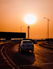 a white car driving down a road at sunset
