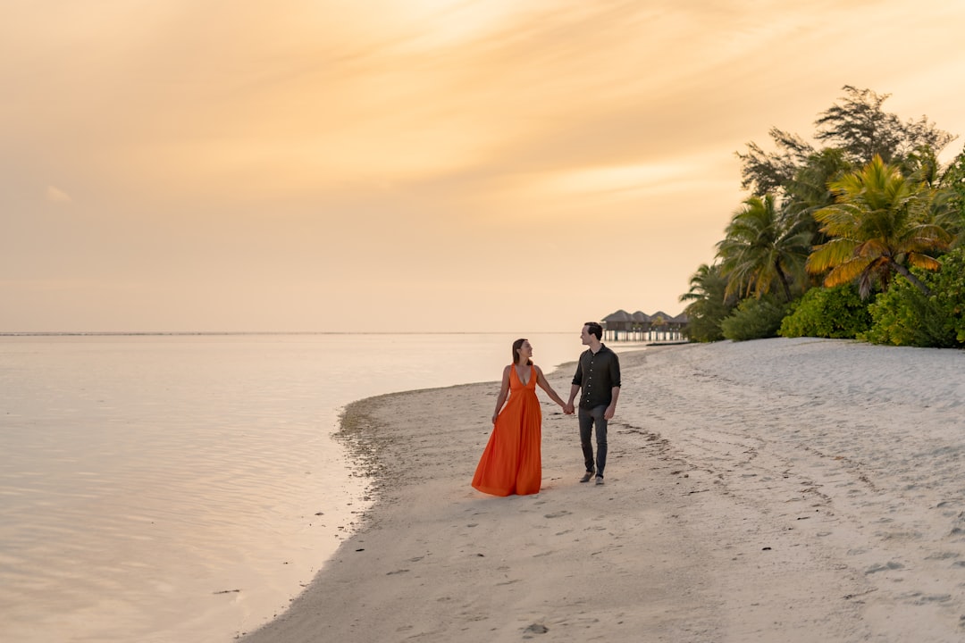 a man and woman walking on a beach holding hands,