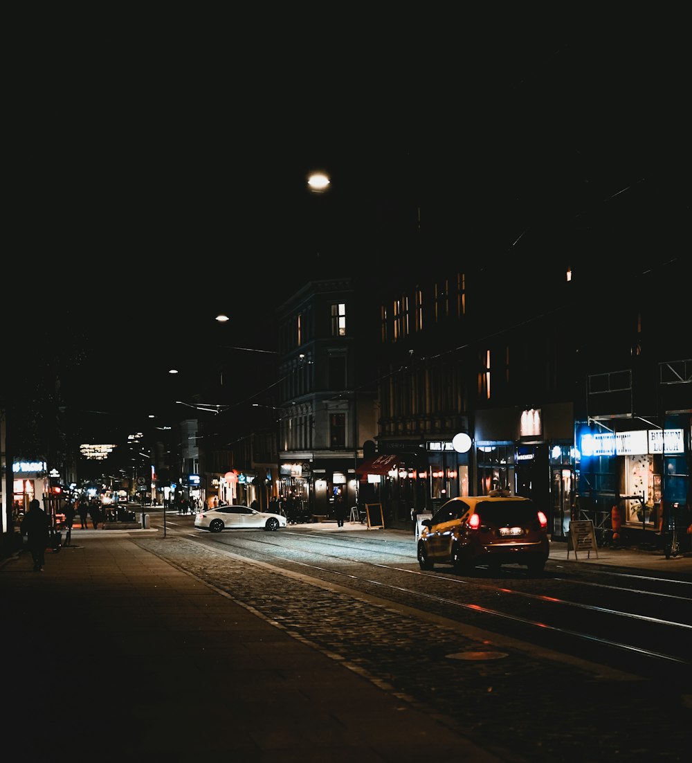 a city street at night with cars parked on the side of the road