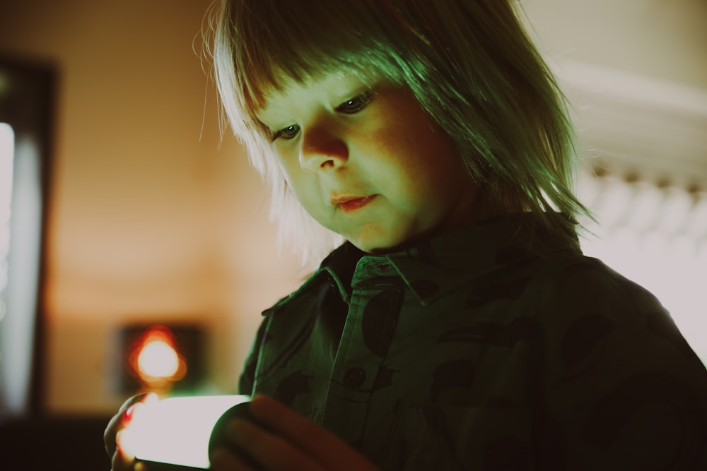 un petit garçon qui regarde un téléphone portable