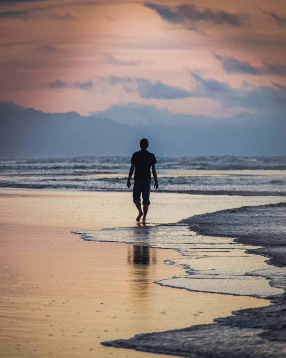 a man walking along a beach next to the ocean