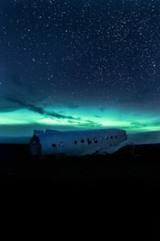 a plane sitting in the middle of a field under a night sky