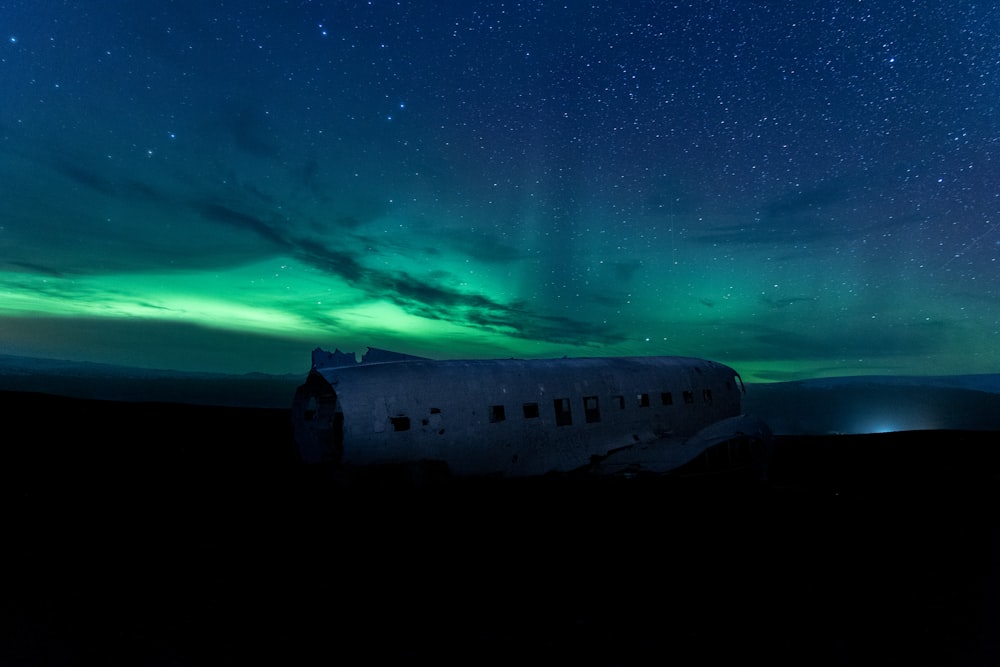a plane sitting on top of a grass covered field under a sky filled with stars
