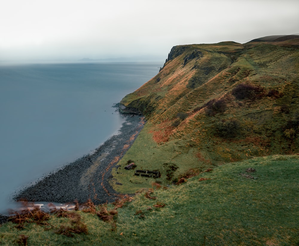 a grassy hill next to a body of water