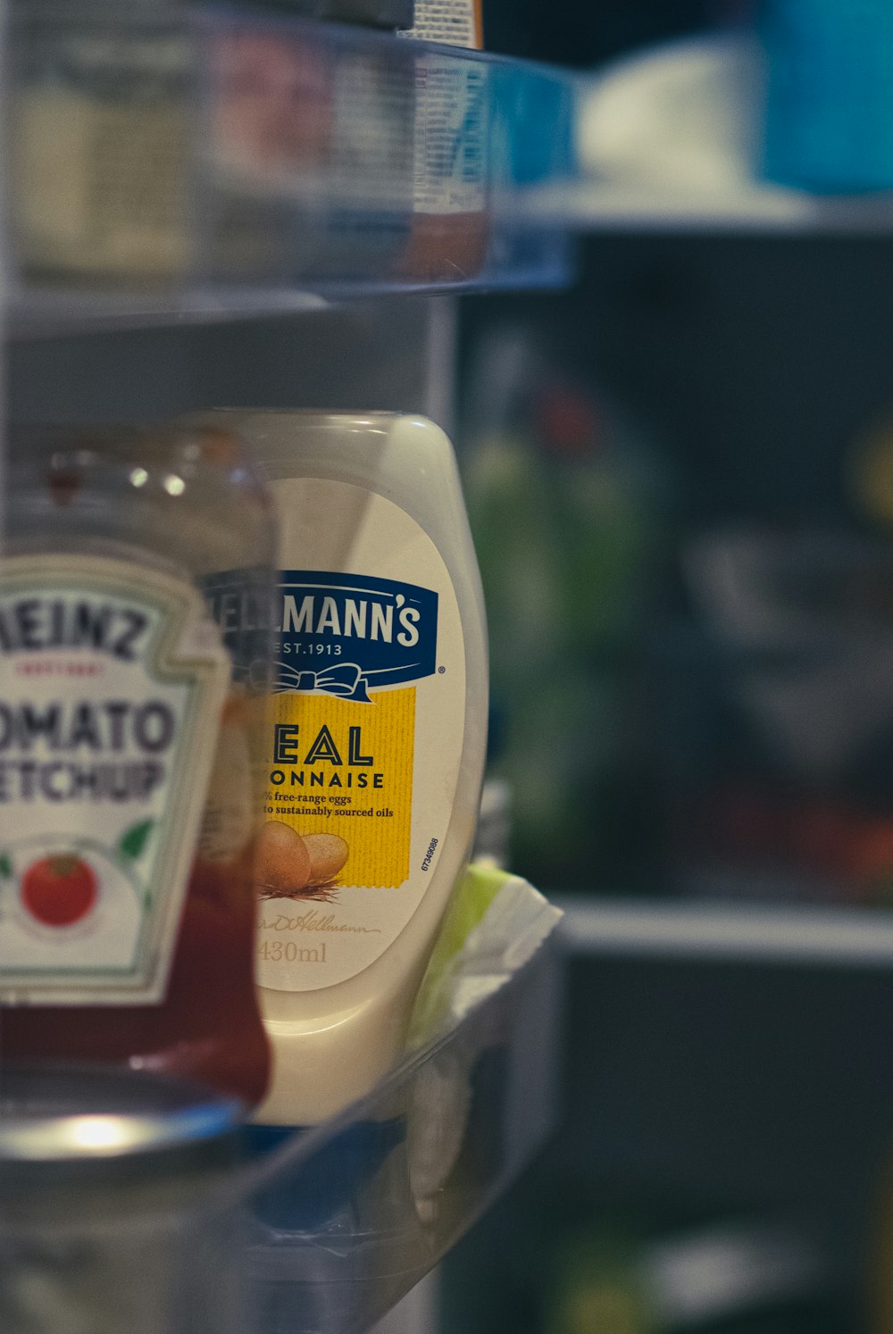 a container of mayonnaise and a bottle of ketchup on a shelf