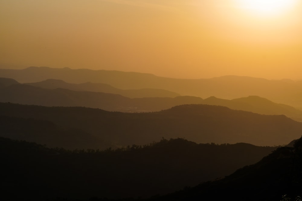 the sun is setting over a mountain range