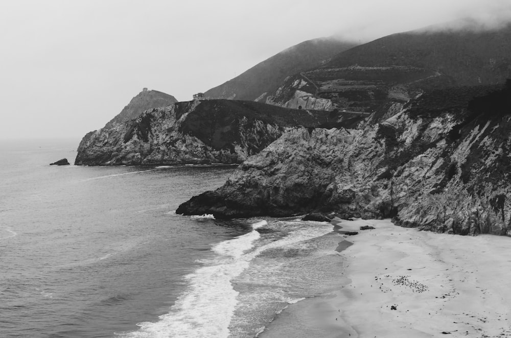a black and white photo of a beach and cliffs