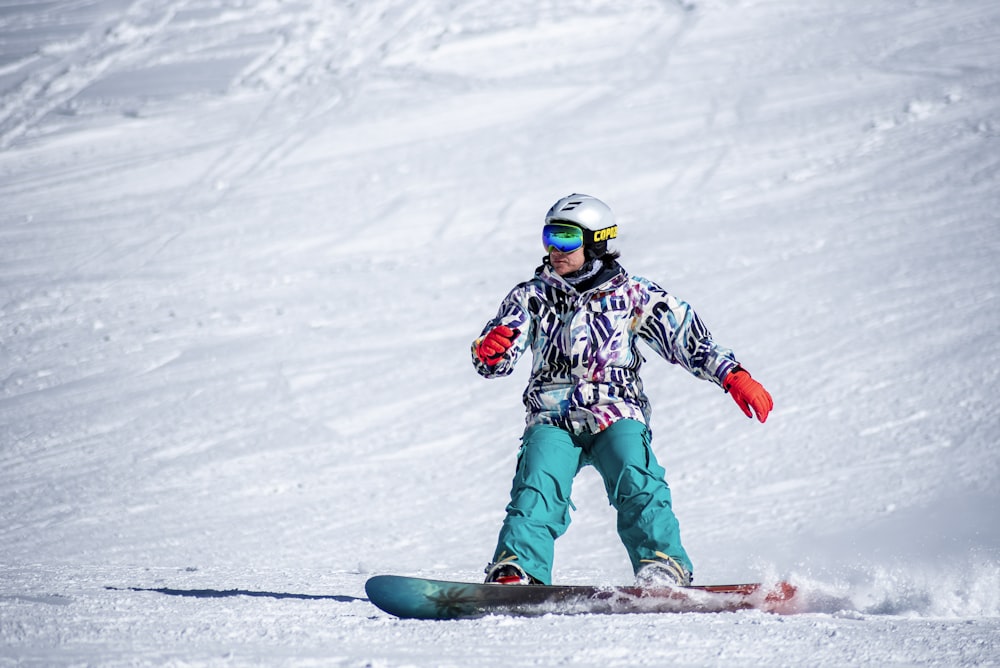 a person riding a snowboard down a snow covered slope