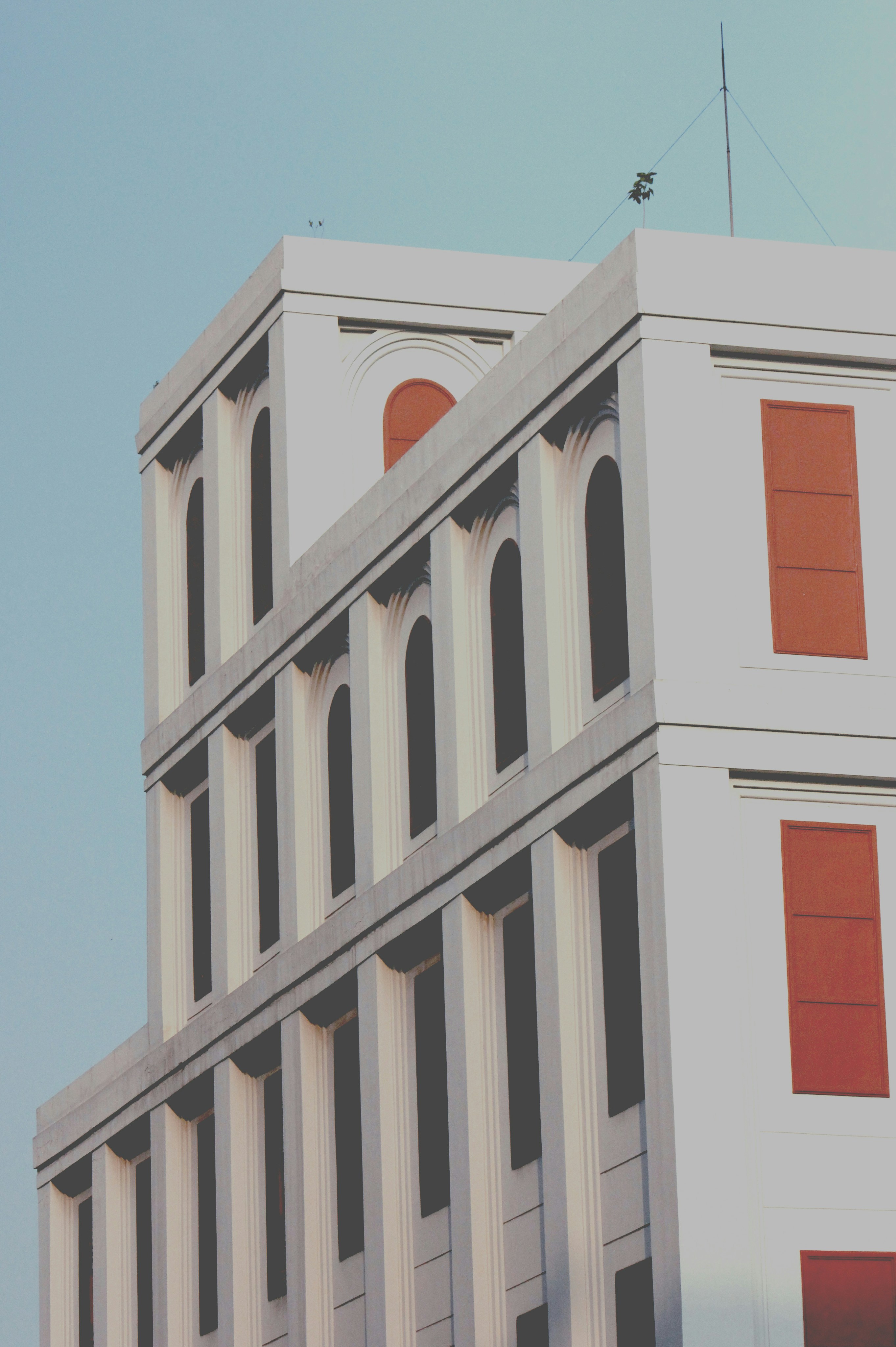 a tall white building with red shutters and a clock