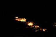 A RefugioVita unit illuminated at dusk, glowing softly against a backdrop of rugged terrain.