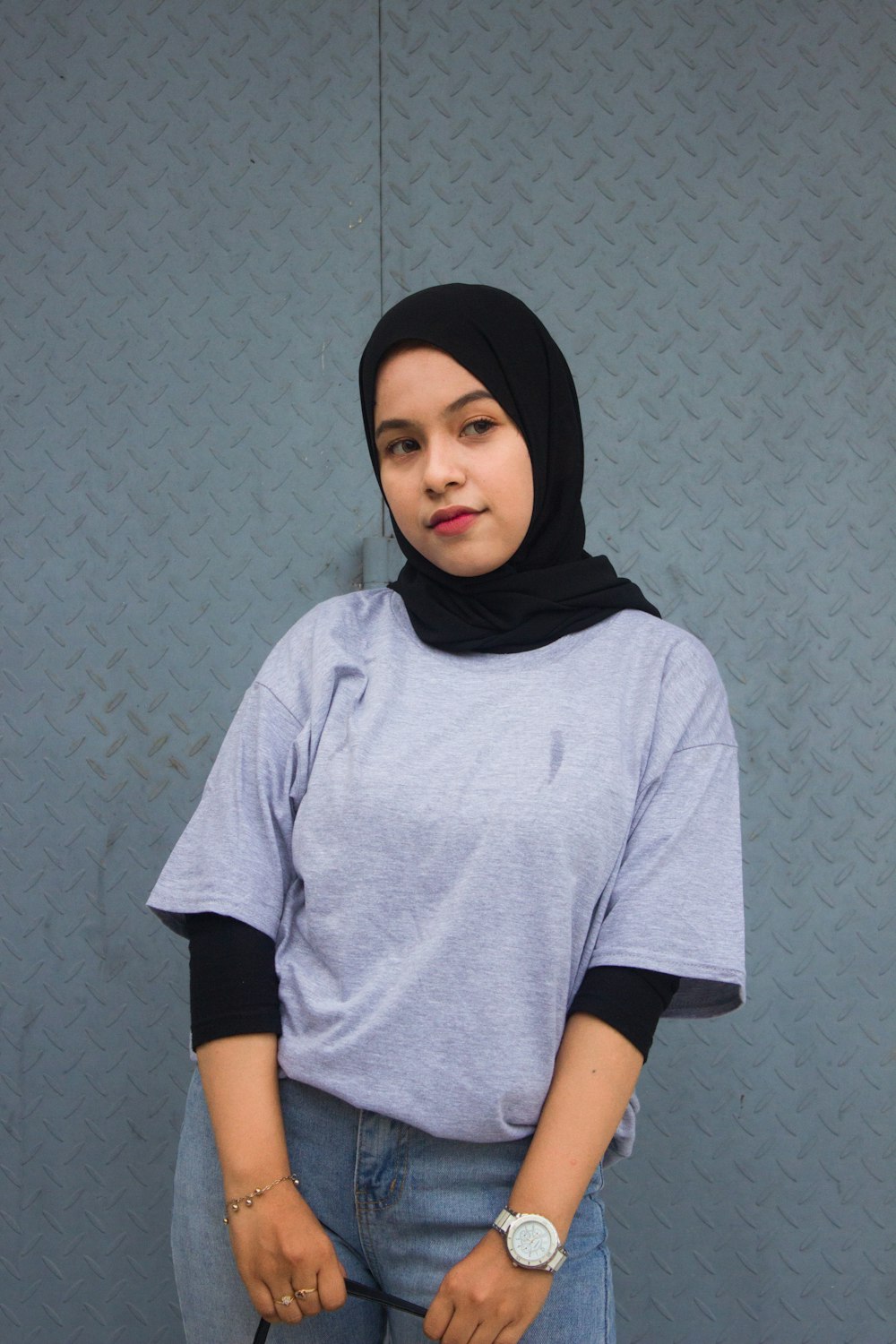 a woman wearing a hijab standing in front of a wall