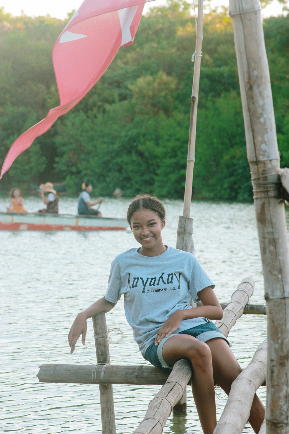 a woman sitting on a wooden dock next to a body of water