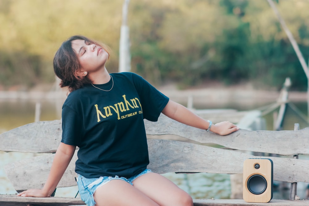 a woman sitting on a wooden bench next to a speaker