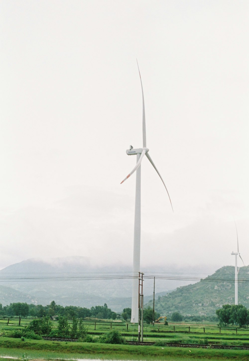 a group of windmills in a field with mountains in the background