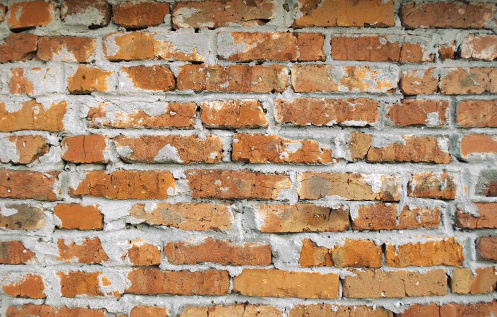 a close up of a brick wall with peeling paint