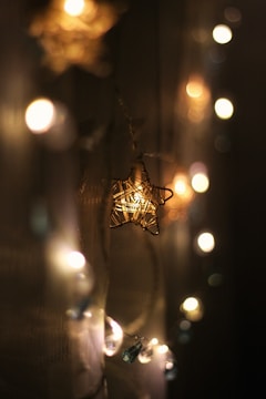 A warmly lit star-shaped light surrounded by a string of blurred lights against a dark background, creating a cozy and intimate atmosphere.