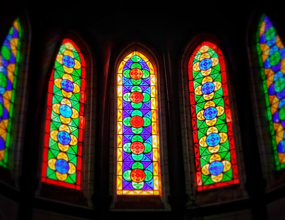 Trois vitraux colorés dans une pièce sombre