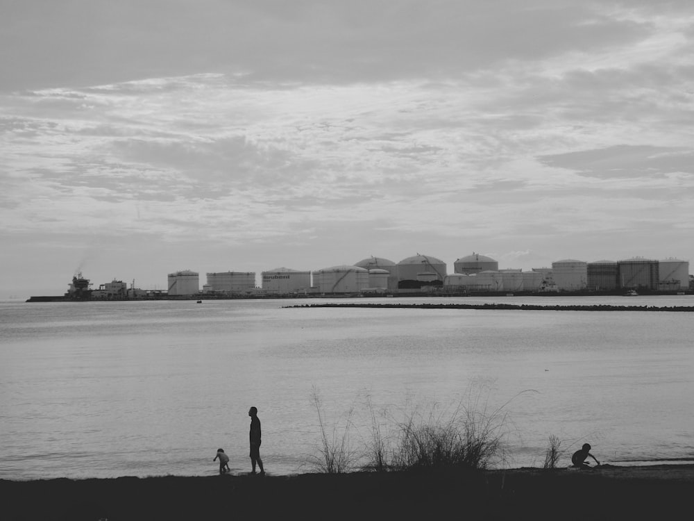 a black and white photo of a man and a child near a body of water