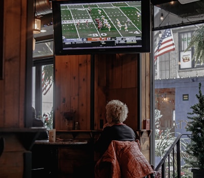 a woman sitting at a bar watching a football game