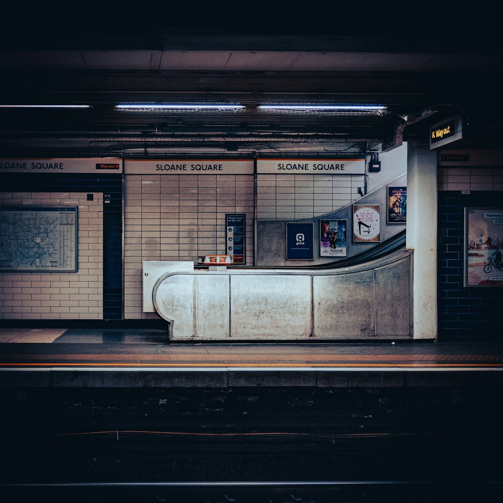 a train station with a bench and a wall